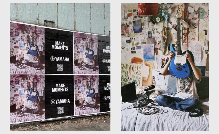 Street art advertisement for Yamaha music featuring a person sitting cross-legged with a blue electric guitar in front of them.