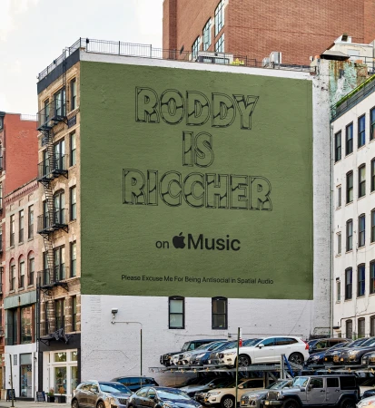 A building-size advertisement featuring the phrase "Roddy is Ricch" for Apple Music is painted on the side of a building in an urban setting.