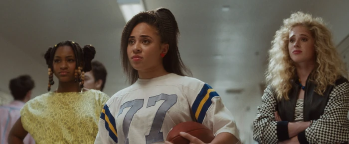 Three young women in a school hallway with a football, featuring post production by Framestore
