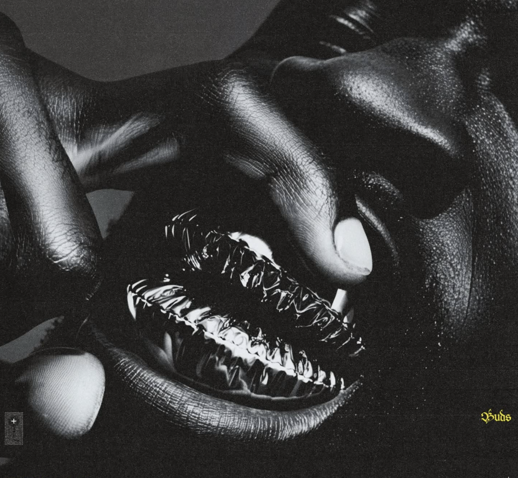 Close-up of adult hands holding metallic lips in a monochrome studio photograph; skin contrasts with a glossy reflective lip prop.