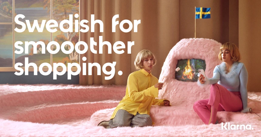 Two people in a surreal setting with a faux fireplace, pink carpeted stairs, and a Swedish flag, promoting smoother shopping.