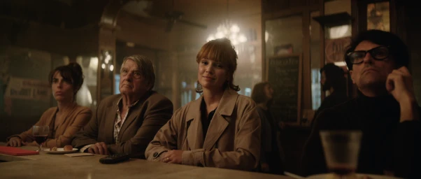 Group of patrons seated at a dimly lit wooden bar counter in a pub, directed by Nick Morissey.