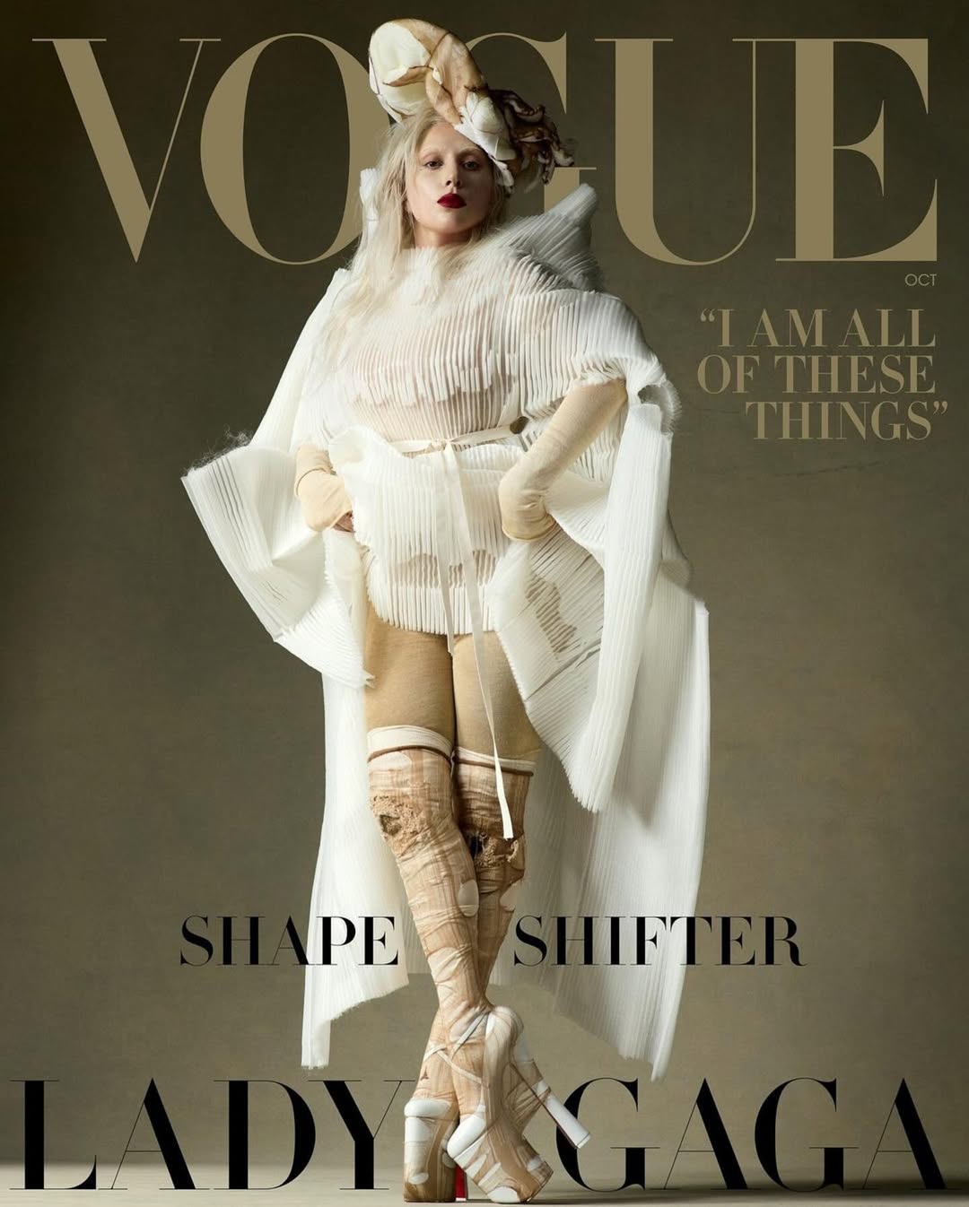 Vogue cover featuring Lady Gaga in a white avant-garde outfit and platform heels against a neutral background. Fashion editorial.