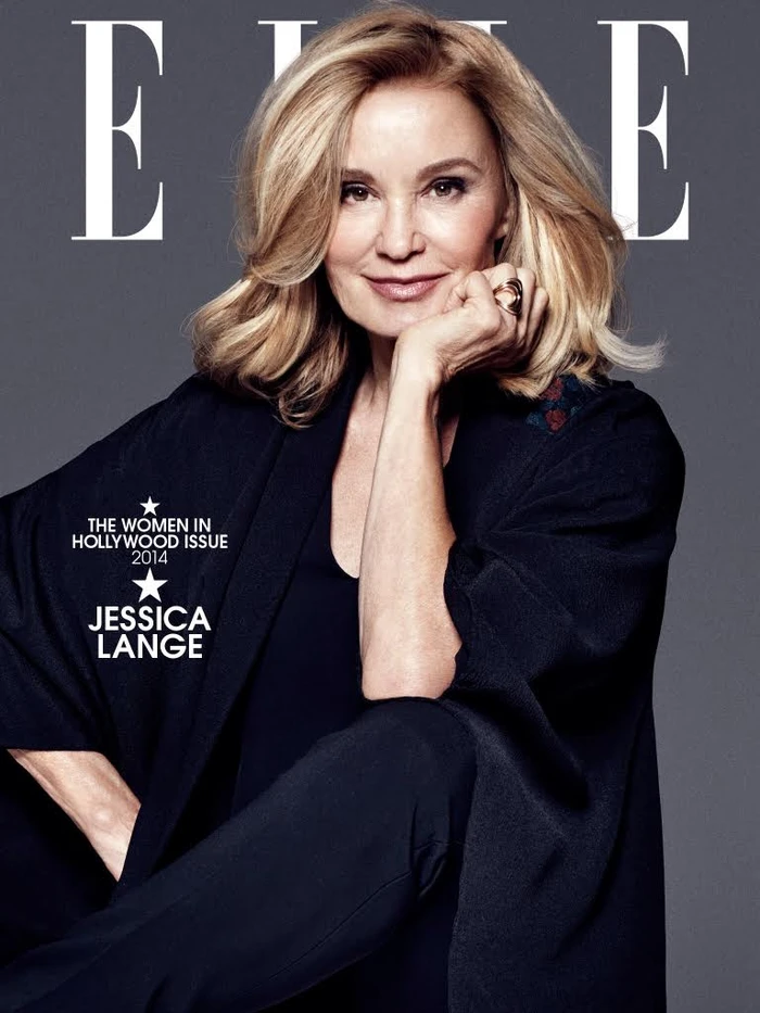 Jessica Lange with blonde hair resting chin on hand wearing a dark top against a grey background for Elle magazine cover.