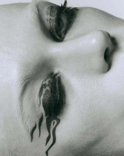 Monochromatic close-up shot featuring a woman's face with artistic makeup forming a dripping paint or tattoo effect under her eye.