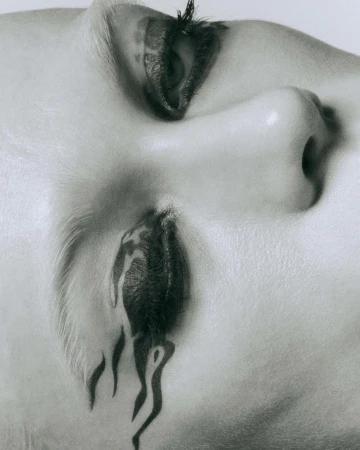 Monochromatic close-up shot featuring a woman's face with artistic makeup forming a dripping paint or tattoo effect under her eye.