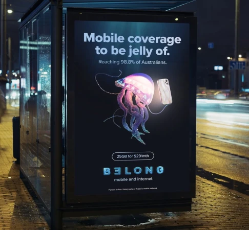 Mobile coverage ad with jellyfish and smartphone. Surreal advertisement on bus stop at night with text promoting internet services.