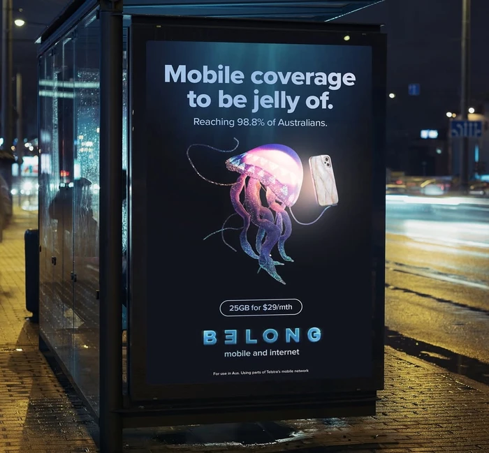 Bus shelter advertisement featuring a glowing jellyfish illustration holding a smartphone next to Belong branding