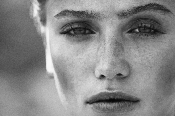 Close-up black and white portrait of a woman with freckles photographed by Jennifer Stenglein.