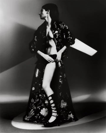 Model in patterned dark jacket and long skirt posing in dramatic studio lighting styled by Freddie Fredericks in New York