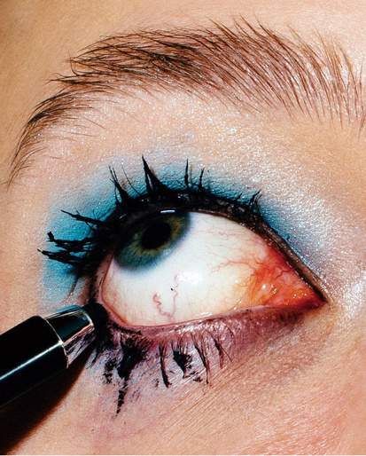 Close-up of a person's eye being lined with black eyeliner, showcasing dramatic eye makeup and a beauty product in use.