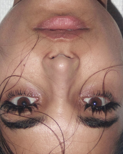 Close up upside down portrait of a woman showing dramatic eyelashes and pink lipstick by make up artist Mayumi Oda