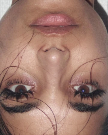 Close up upside down portrait of a woman showing dramatic eyelashes and pink lipstick by make up artist Mayumi Oda