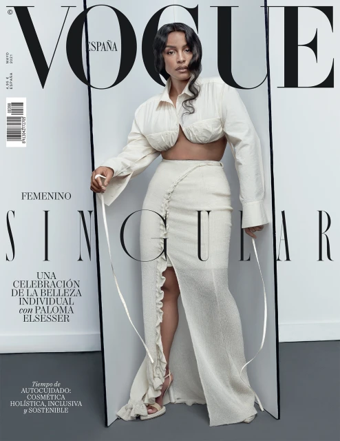 Vogue España cover featuring Paloma Elsesser in a white ensemble, posing against a grey backdrop, with the Vogue logo prominently displayed.