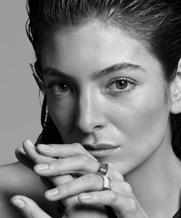 Close-up monochrome portrait of a woman with wet hair posing with hands under chin, wearing multiple rings.
