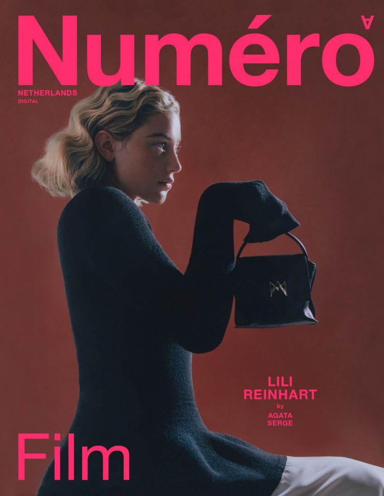 Magazine cover featuring Lili Reinhart in a side profile, wearing a black top and holding a black handbag against a muted red background.