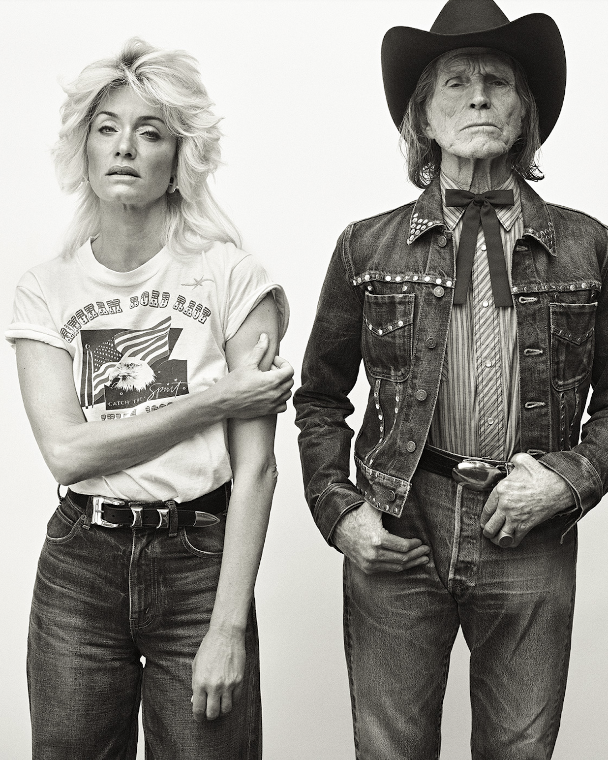 A vintage-style portrait features an adult female with blonde hair and an adult male with a cowboy hat and denim jacket against a plain backdrop.