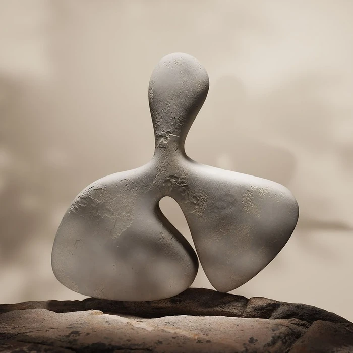 Abstract off-white sculptural object with organic curved forms resting on a textured rocky base against a soft gradient wall.