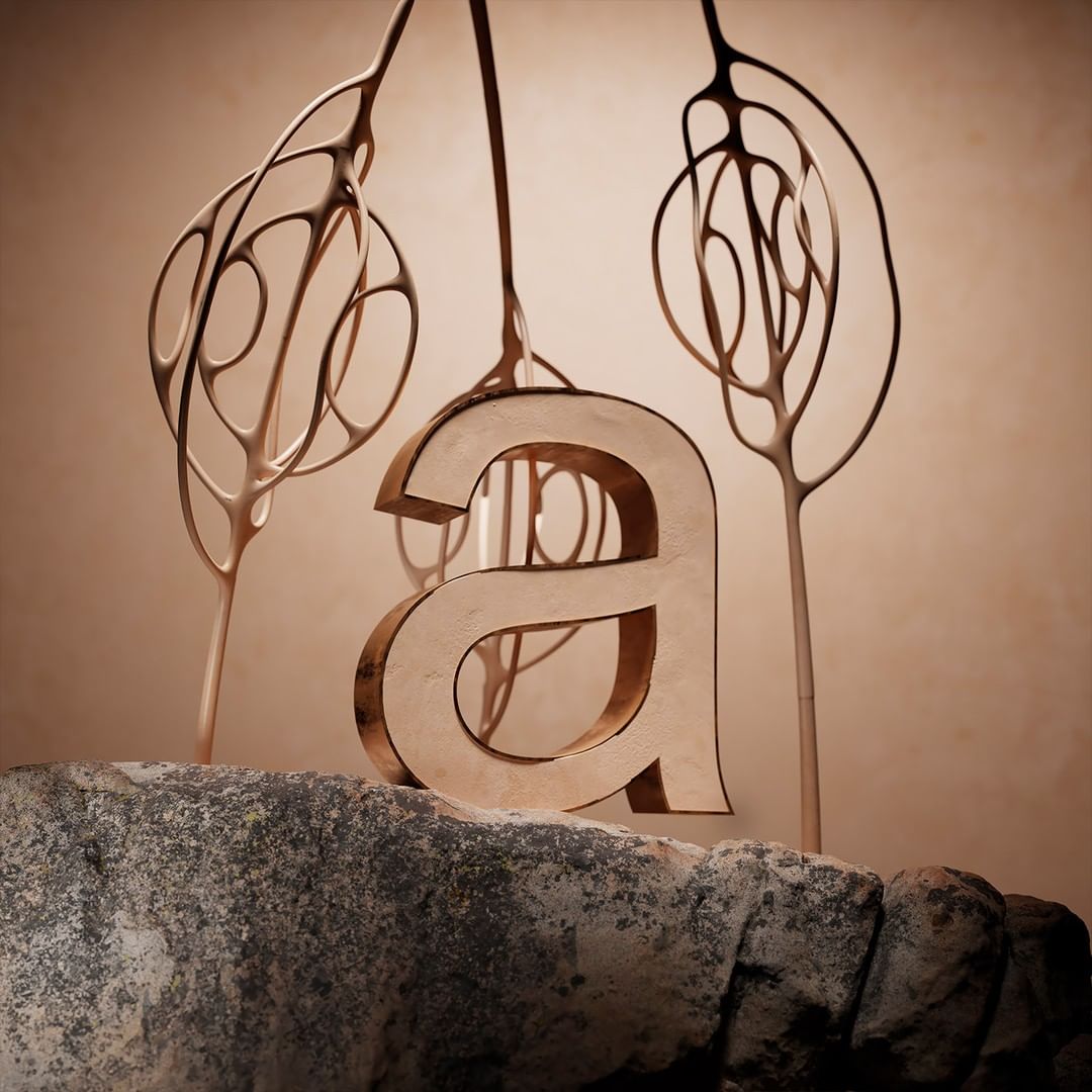 Abstract sculptural arrangement featuring a prominent letter 'a' atop a textured stone surface, complemented by organic, branch-like forms.