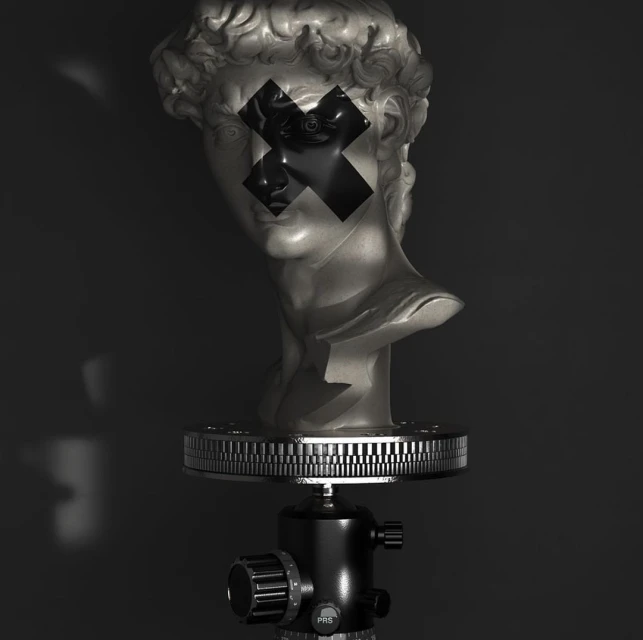 Bust sculpture on a tripod with black tape 'X' across the eyes, shot in a low-key style against a dark backdrop with faint lighting.