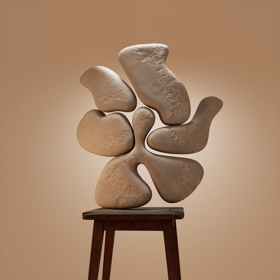 Abstract sculpture made of stone-like material is balanced on a dark wood stool against a neutral beige background with soft studio lighting.