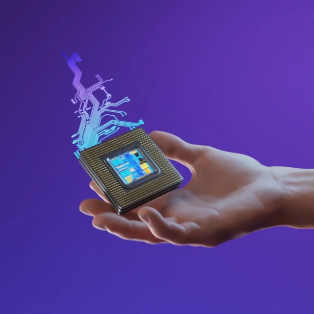 A hand holds a computer chip with electronic circuit-like designs on a purple background, showcasing technology and innovation.