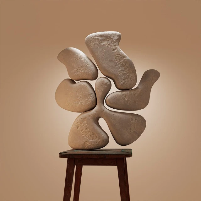 Abstract organic stone shapes, stacked on a small wooden stool, in a studio setting with warm lighting and a neutral background.