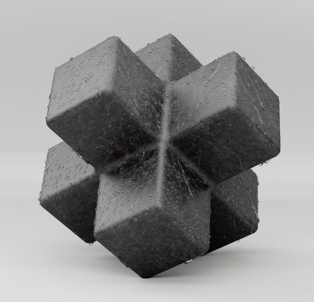 Close-up studio shot of a geometric cube-shaped object made of dark gray material with water droplets on a light gray background.