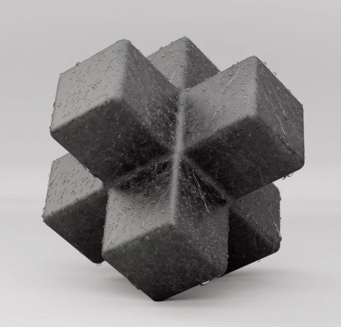 Close-up studio shot of a geometric cube-shaped object made of dark gray material with water droplets on a light gray background.