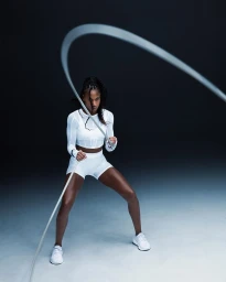 Black woman in athletic wear waving a heavy workout rope against a gradient studio backdrop