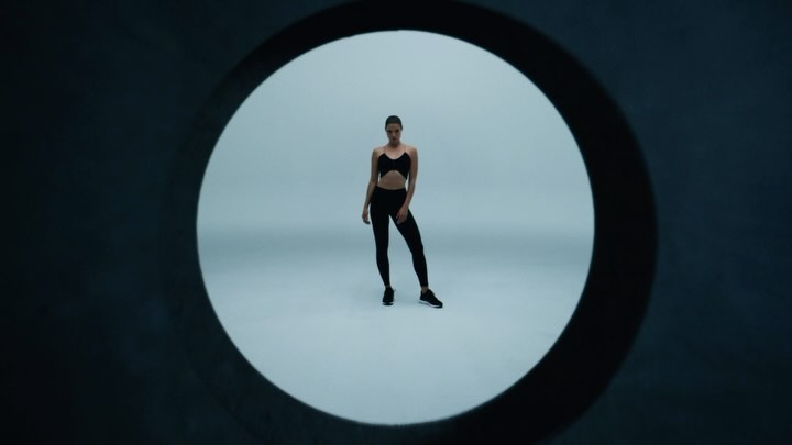 Athletic woman in fitness apparel poses in a cutout against a light backdrop, highlighting sportswear and studio lighting for fitness visuals.