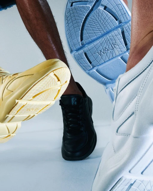 A group of multicolored WALAA footwear in white, beige, black, and light blue with soles prominently displayed on a light background.