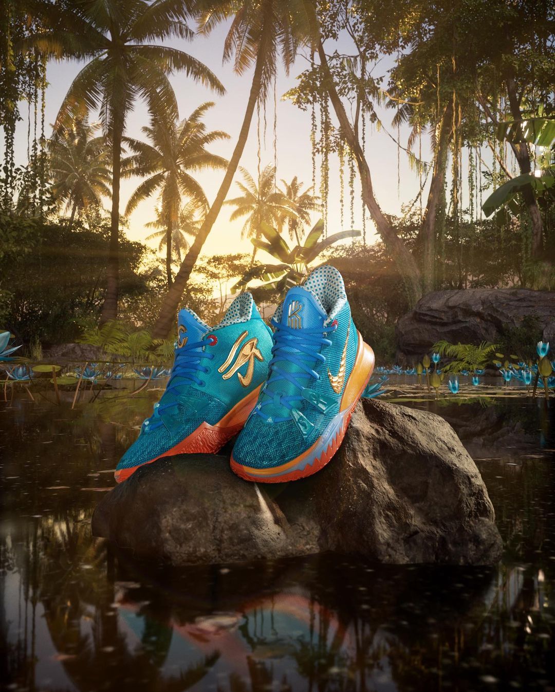 Pair of blue and gold sneakers on a rock, surrounded by lush tropical foliage and a pond reflecting the sky and palm trees.