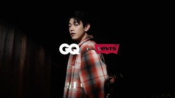Adult male model in a photo studio wearing a red and gray plaid shirt with the GQ and Levis logos in the foreground.