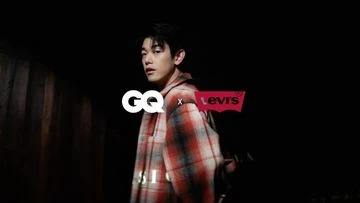 Adult male model in a photo studio wearing a red and gray plaid shirt with the GQ and Levis logos in the foreground.