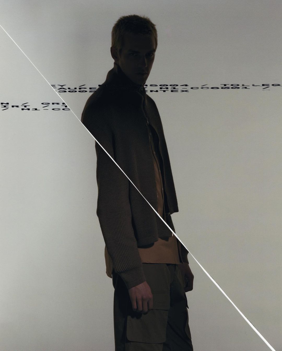 Man standing in shadow against a light background with overlaid text lines