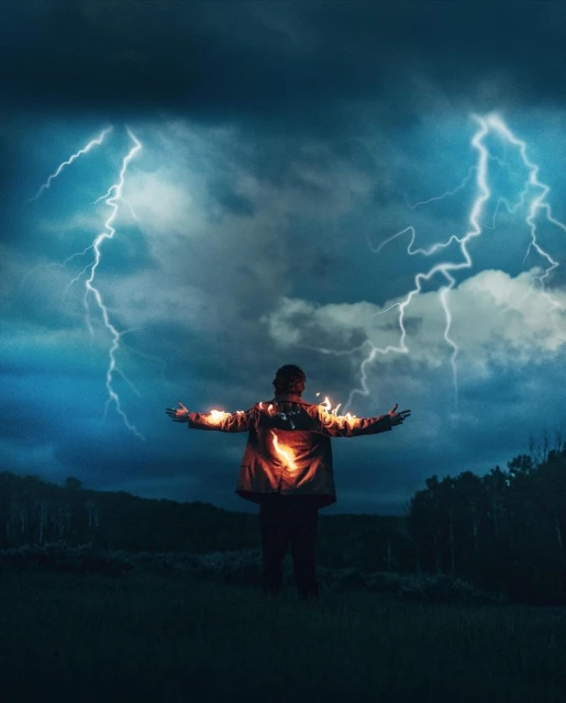 Person stands in a field under stormy sky with lightning. Adult with arms outstretched wearing jacket. Nature and weather concept.