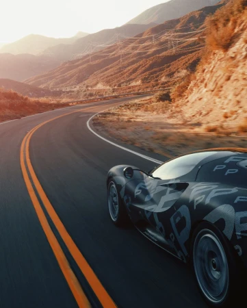 Sportscar races along an open road through a mountain landscape, bathed in warm sunlight. Motion blur on the wheels enhances the sense of speed.