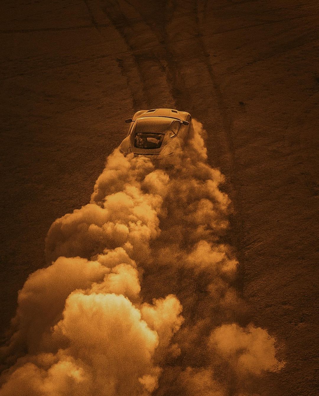 Car races through a desert landscape, kicking up a plume of dust, creating a dynamic and exciting off-road scene in sepia tones.