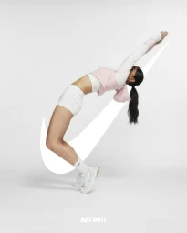 A woman in white shorts and pink top arches her back over a giant Nike swoosh logo on a white background
