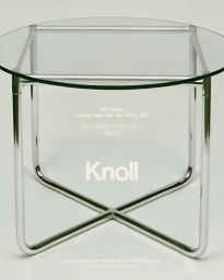 A modern glass top side table with polished chrome tubular steel legs against a plain white background.