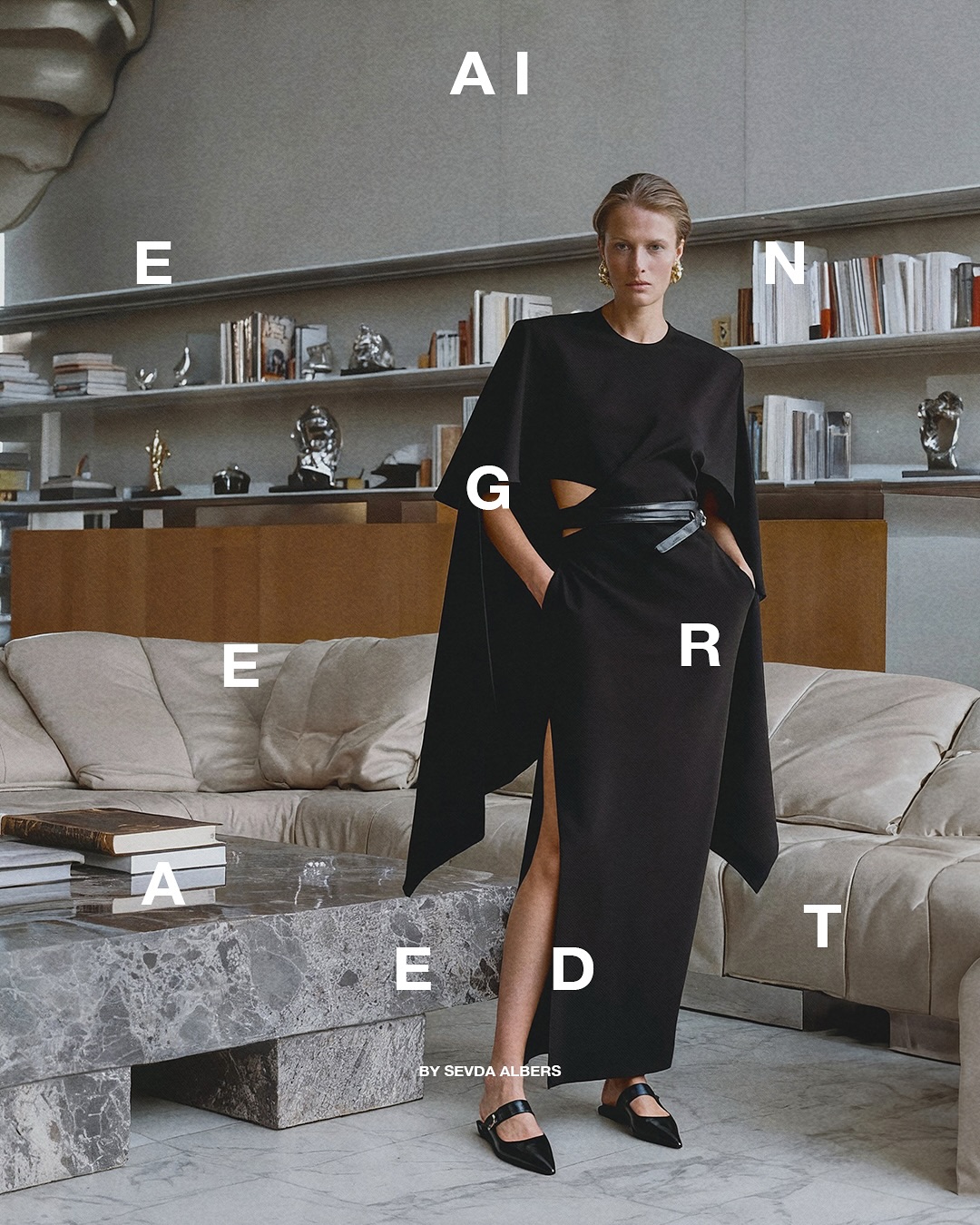 A woman in a black cut-out dress poses indoors with neutral walls, books, and a stone table for a fashion editorial shot.
