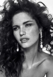 Close-up monochrome portrait of a woman with curly dark hair and dangling crystal earrings by Sera Zelva