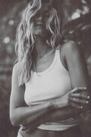 Monochrome portrait of a woman with tousled hair wearing a white ribbed tank top, photographed by Aaron Feaver.
