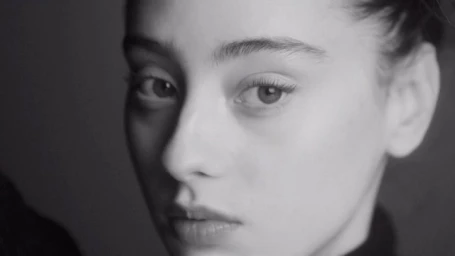 Close up monochrome portrait of a young woman looking directly at the camera with a serious expression.
