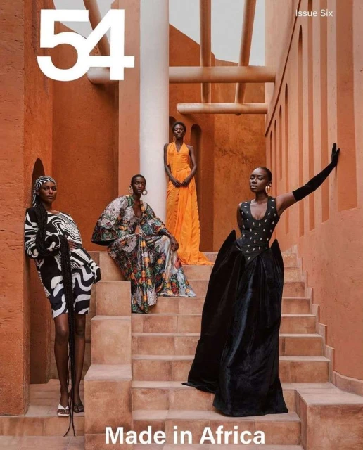 Fashion editorial featuring four Black female models on a terracotta staircase wearing vibrant designer dresses and dramatic poses, African theme.