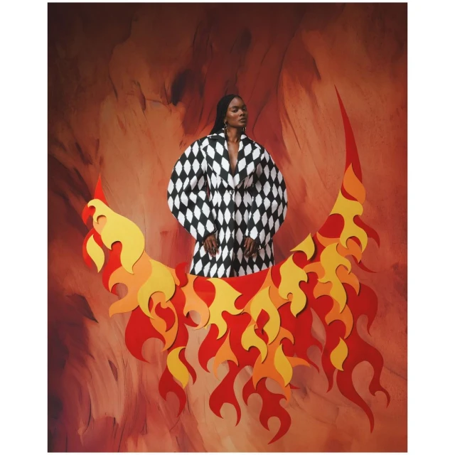 Elegant Black woman poses in a black and white harlequin jacket in front of a swirling red background and fiery crescent moon prop.