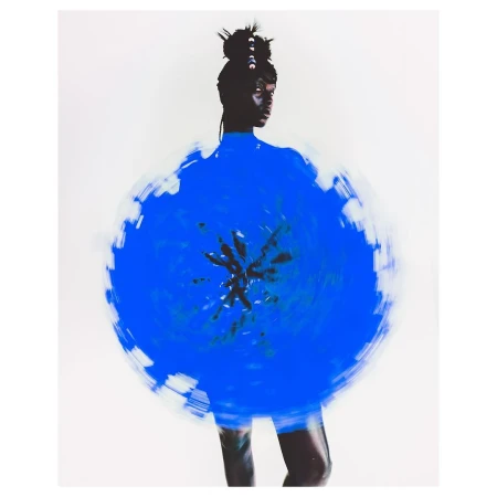 Artistic studio shot of a woman with dark skin wearing a blue circular garment against a neutral background. Long exposure effect.