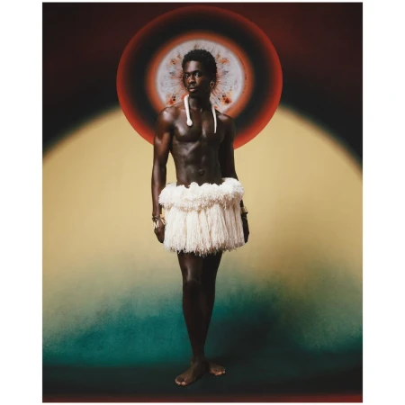 Striking studio shot of a Black male model in traditional wear: bare-chested, grass skirt, and beaded jewelry, against a vibrant backdrop.