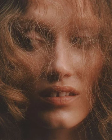 Close-up portrait of a woman with wispy blonde hair falling across her face shot by photographer Aart Verrips.